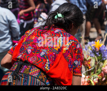 Una mujer en el mercado de domingo en Chichicastenango, Guatemala lleva el tradicional tejido colorido huipil o blusa de esa ciudad. Foto de stock