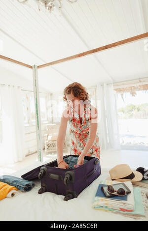 Mujer desembalaje maleta en la cabaña en la playa dormitorio Foto de stock