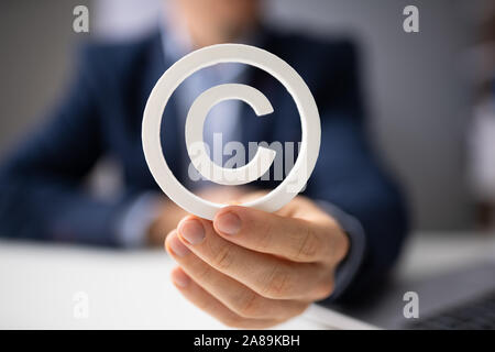 Persona sosteniendo el signo de copyright en mano blanca Foto de stock