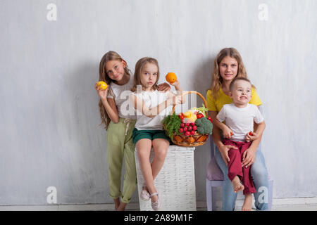 Muchacho y tres niñas con una canasta de frutas y verduras Foto de stock