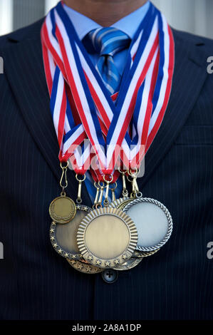Premio Empresario irreconocible de pie con medallas amontonado en sobre su traje Foto de stock