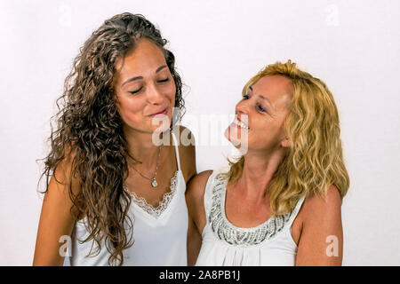 Intenso momento de complicidad entre madre e hija vestida de blanco sobre un fondo blanco.