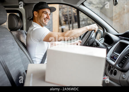 Hombre de entrega de conducción de vehículos de carga con bultos en el asiento del pasajero, vista interior del vehículo en los cuadros con espacio en blanco