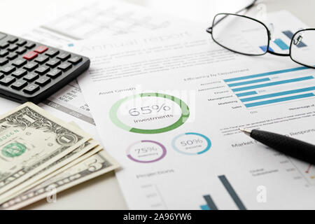 Boceto financiero de inversiones informe de gráficos de hoja con pluma visible, calculadora, anteojos y billetes de dólar. Contabilidad, negocios, finanzas e impuestos