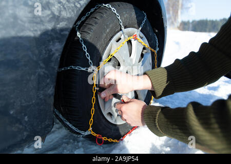 Automóvil atascado en la nieve caída. Neumático equipado con cadenas para la nieve. Foto de stock