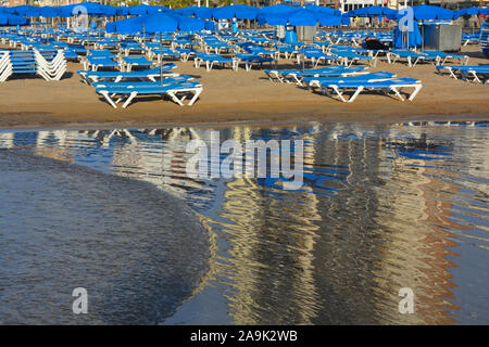 Hamacas y sombrillas en la Playa de Levante, reflexionó sobre la arena mojada en la madrugada, Benidorm, Alicante, España Foto de stock