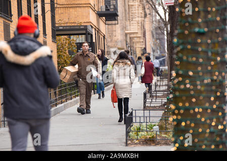 La CIUDAD DE NUEVA YORK - 14 de diciembre de 2018: la ciudad de Nueva York Street Scene en el tiempo de Navidad con conductor de UPS entrega de paquete de Amazon, peatones y luces en t Foto de stock