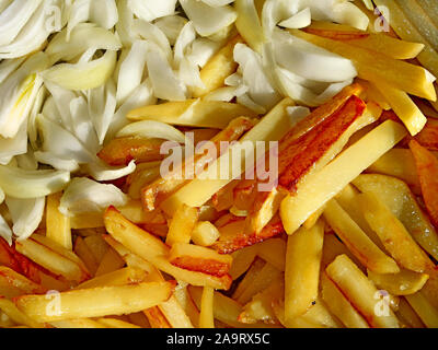 Chips de patata frita con corteza dorada y cortar cebollas mientras cocina cerca, a la brillante luz del sol