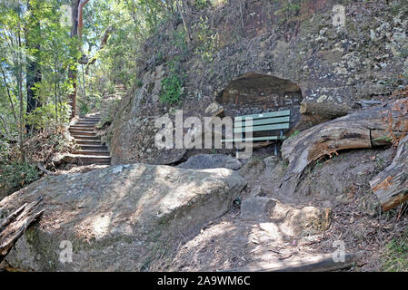 Subiendo por una escalera de piedra y madera banqueta pacíficas anidan debajo de una roca saliente en la pista de caminar Benowie Ku-Ring-Gai National Park, Nuevo modo Foto de stock