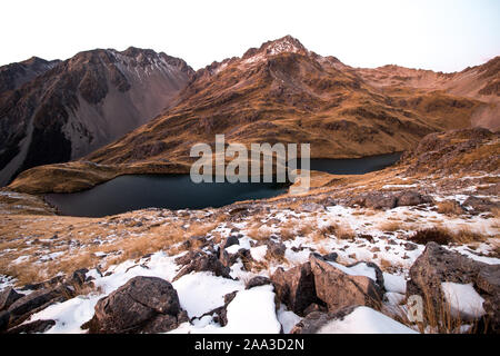 Dos tarns de montaña en medio ambiente alpino de Nueva Zelanda, con un pico de los Alpes por encima de ellos en otoño con poca nieve. Ángelus lagos, Nelson Lagos NP