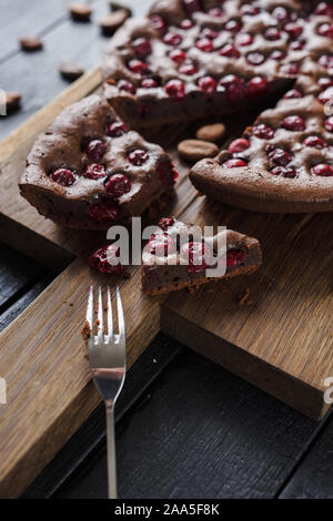 Brownies de chocolate con cerezas ácidas y habas de cacao en el fondo quemado un alto ángulo de visualización Foto de stock