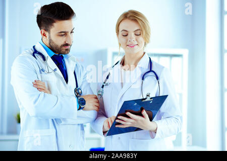 Dos médicos sosteniendo una carpeta y hablando de paciente Foto de stock