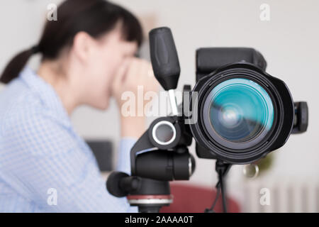 Cerrar imagen de cámara DSLR Sobre trípode con la mujer trabajadora fotógrafo o diseñador en la parte posterior de la pantalla borrosa y escena en segundo plano. Foto de stock