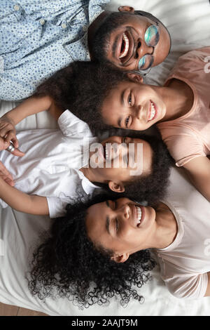Vista superior de la risa retrato de familia africana acostada en la cama