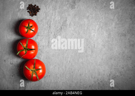 Tres tomate con gotas. Máxima profundidad de campo. Frescos rojos tomates maduros para su uso como ingredientes de cocina en primer plano con copyspace sobre dark backgrou Foto de stock