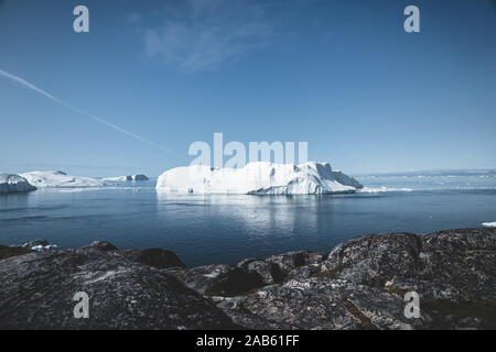 Naturaleza del paisaje ártico con icebergs en Groenlandia icefjord con sol de medianoche atardecer amanecer en el horizonte. Temprano en la mañana de verano durante alpenglow