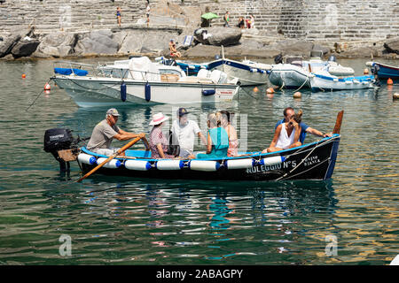 Vernazza village. Hombre local filas en una pequeña embarcación de madera con seis turistas a bordo. El parque nacional de Cinque Terre, en Liguria, La Spezia, Italia, Europa