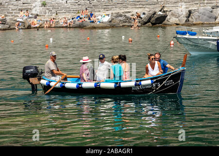 Vernazza village. Hombre local filas en una pequeña embarcación de madera con seis turistas a bordo. El parque nacional de Cinque Terre, en Liguria, La Spezia, Italia, Europa