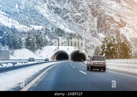 En invierno el paisaje con túnel de carretera alpina, bosque, montañas y cielo azul sobre fondo en frío brillante día soleado. Viaje en coche viaje viajar en familia.