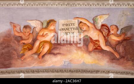 COMO, Italia - 8 de mayo de 2015: el fresco de los ángeles con la inscripción del Viejo Tstament desde el techo de la iglesia Basilica di San Fedele.
