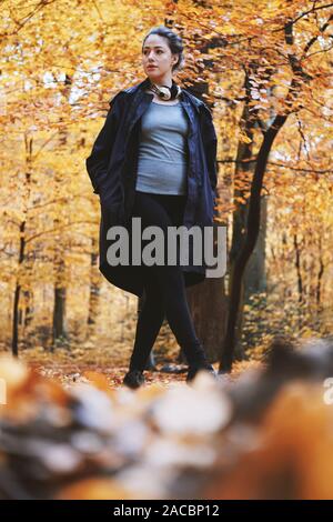 Mujer joven disfrutando de otoño de caminar en el bosque - cándido estilo de vida al aire libre en temporada de otoño - ángulo bajo vista de longitud completa Foto de stock