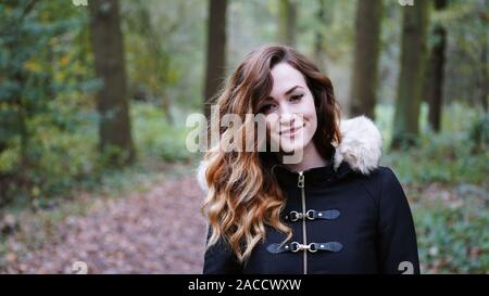 Feliz joven vistiendo abrigo de ir a dar un paseo en el bosque en un frío día de otoño Foto de stock