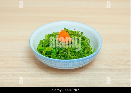 Chuka wakame salad con ebiko en la taza sobre la mesa de madera Foto de stock