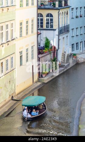La pequeña embarcación con turistas en el canal Čertovka en Lesser Town, Praga, República Checa.