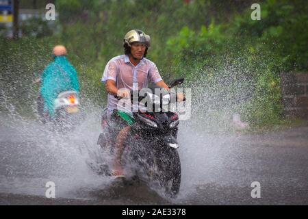 MUI NE, Vietnam - Noviembre 3, 2016: Un motociclista paseos a lo largo de una calle inundada en Noviembre 3, 2016 en Mui Ne, Vietnam. Foto de stock