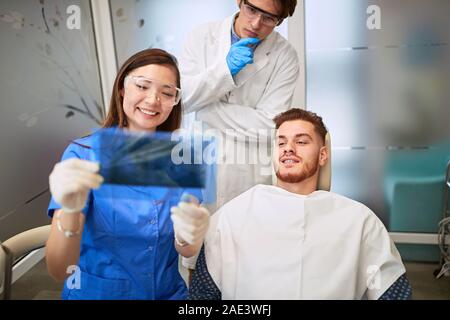 Dentista con ayudantes en busca del paciente con rayos X de los dientes Foto de stock