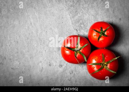 Tres tomate con gotas. Máxima profundidad de campo. Frescos rojos tomates maduros para su uso como ingredientes de cocina en primer plano con copyspace sobre dark backgrou Foto de stock