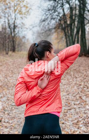 Mujer joven estiramientos antes de correr al aire libre en un frío día de otoño