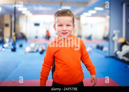 Retrato de niño posando en el gimnasio. El tema es el desarrollo físico de los niños. Un deportista boy en ropa deportiva está mirando a la cámara. Infancia y