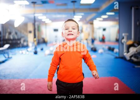 Retrato de niño posando en el gimnasio. El tema es el desarrollo físico de los niños. Un deportista boy en ropa deportiva está mirando a la cámara. Infancia y