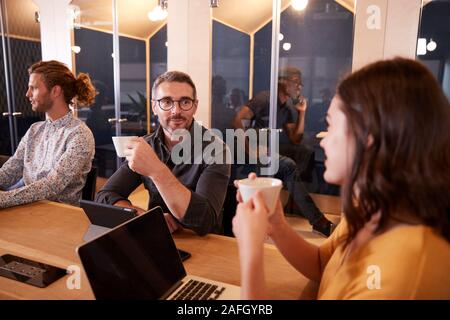 Creative colegas tomando café y hablando en su oficina, cerca de la cantina, el enfoque selectivo Foto de stock