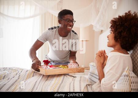 Pareja de Americanos Africanos milenario celebrando, el hombre llevando a su compañero el desayuno en la cama, cerrar