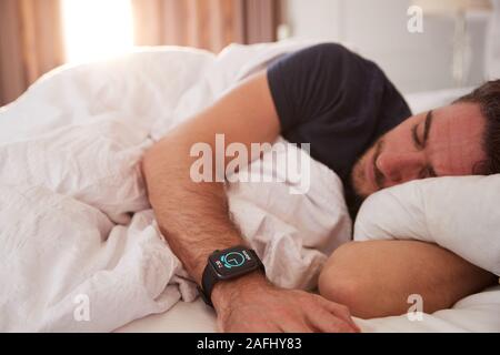 Hombre dormido en la cama usando Smart Watch como Sun rompe a través de las  cortinas Fotografía de stock - Alamy
