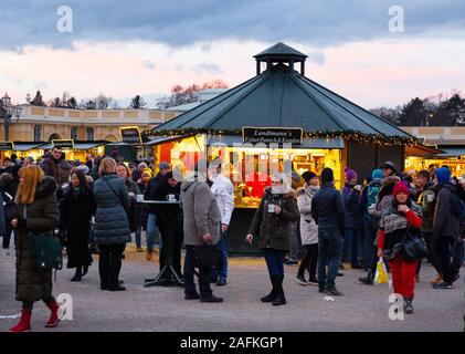 La gente compra y bebe Gluhwein al atardecer, en el mercado de Navidad, Palacio Schonbrunn Viena Austria Europa