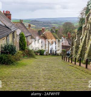Empinadas calles empedradas con casas de techos de paja, Gold Hill, Shaftesbury, Dorset, Reino Unido en diciembre Foto de stock