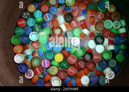 Gran número de soda tapones para botellas de plástico flotando en el agua en un recipiente Foto de stock