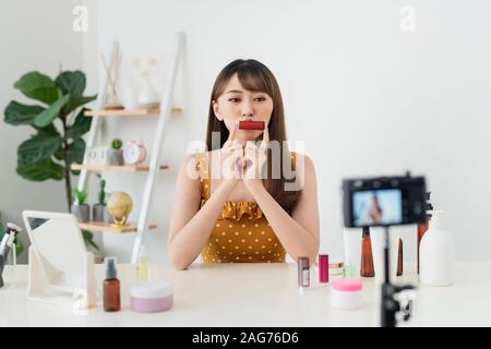 Chica videoblogger blogger de belleza o los registros de vídeo para los suscriptores. Ella muestra el lápiz de labios y explica cómo usarla correctamente. Foto de stock
