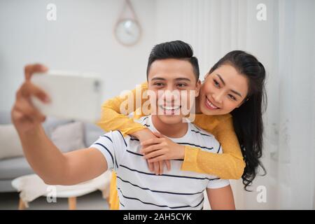 La feliz pareja haciendo un selfie en Livingroom Foto de stock