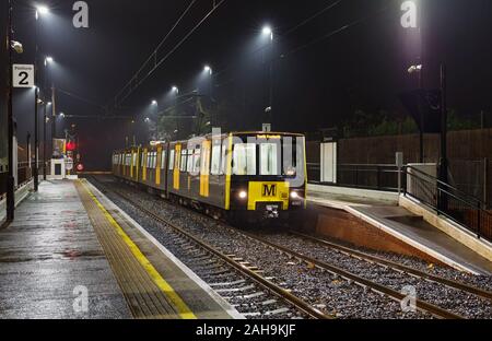 Nexus Tyne y desgaste vagones de Metro 4082 + 8.069, en el banco de pie en una estación húmeda oscura noche Foto de stock