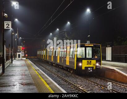 Nexus Tyne y desgaste vagones de Metro 4082 + 8.069, en el banco de pie en una estación húmeda oscura noche Foto de stock