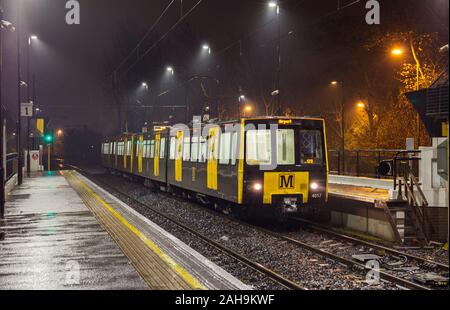 Nexus Tyne y desgaste vagones de Metro 4017 + 4054 en banco, estación de pie en una oscura noche húmeda Foto de stock