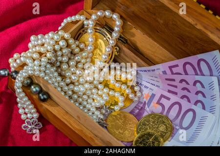 Oro en Münzen und estéril Schmuck mit rotem auf Samt. Symbolfoto für Reichtum, Luxus, Reichensteuer, 500 euros Scheine,