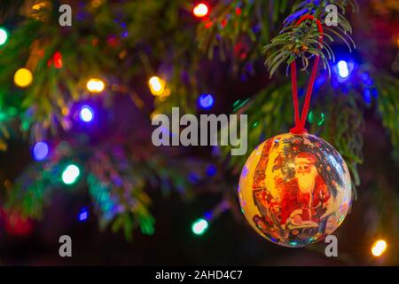 Solo adornos hechos a mano colgando de la rama de un árbol de Navidad con luces de hadas fuera de foco en el fondo