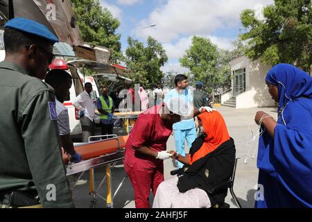 Mogadiscio, Somalia. 29 dic, 2019. Un trabajador médico comprueba una mujer herida en un hospital de Mogadiscio, capital de Somalia, 29 de diciembre de 2019. Un atentado suicida en la capital de Somalia, el sábado han dejado al menos 79 muertos, 149 heridos hasta el momento. Y los somalíes y los líderes de la ONU han condenado el ataque terrorista. Crédito: Hassan Bashi/Xinhua/Alamy Live News Foto de stock