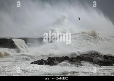 Las olas y el viento tormentoso splash spray contra ocean pier desde el norte de Portugal.