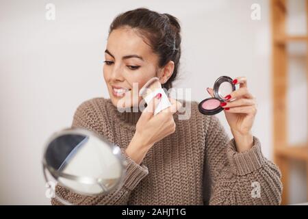 Retrato de mujer sonriente aplicar polvos y colorete mientras hacen hacer en casa, espacio de copia Foto de stock